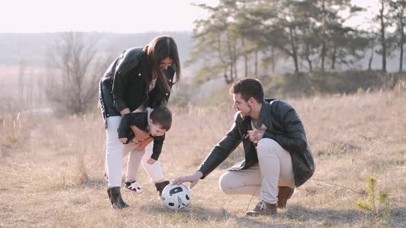 Happy Parents and a Cute Son Are Playing Football Outside