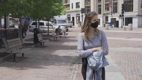 Girl walks alone on sidewalk with black protection mask during corona pandemic