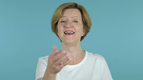 Old Woman Inviting Customers with Both Hands Isolated on Blue Background