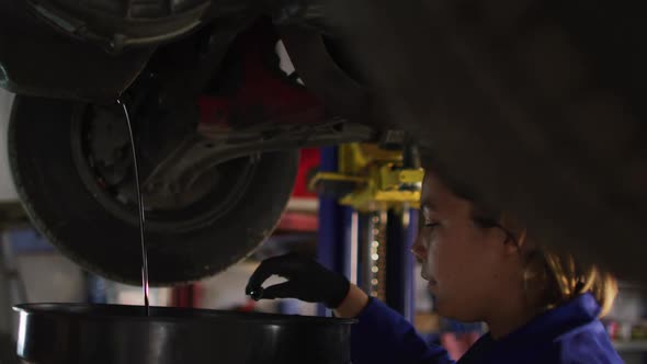 Female mechanic changing oil of the car at a car service station