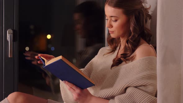 Woman Reading Book Sitting on Windowsill at Home