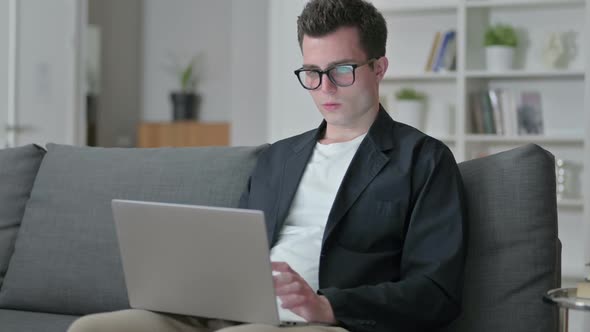 Young Male Designer Doing Video Call on Laptop at Home