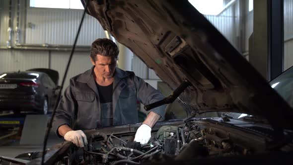 Waist up portrait view of the serious car mechanic in his repair shop