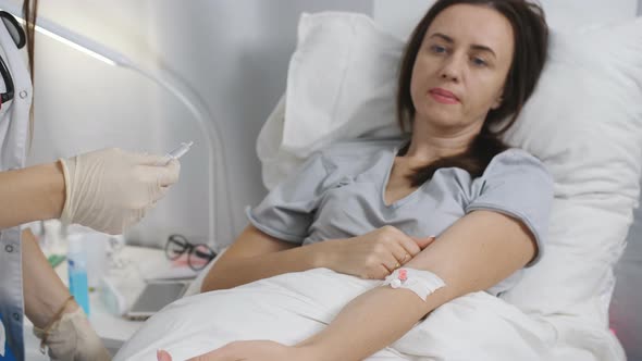 Doctor Putting a Drip Into the Catheter Lying Patients