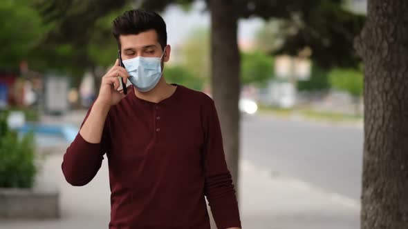 Portrait of Young Man with Face Mask Using Smartphone