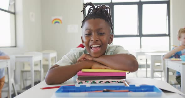 Video of happy african american boy sitting at school desk