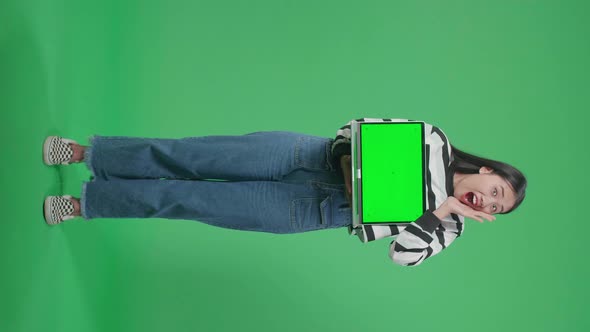 Full Body Of A Smiling Asian Woman Surprised While Holding Green Screen Computer In The Green Screen