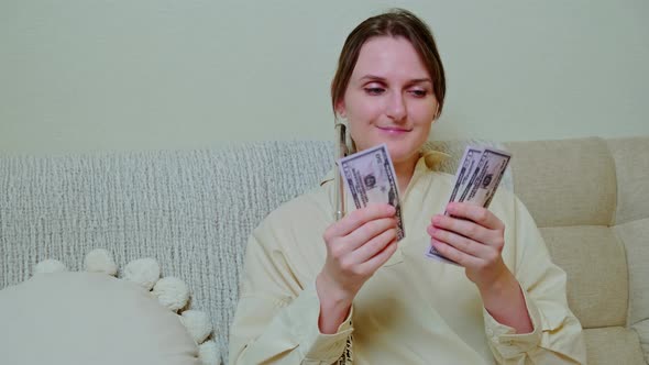 Woman musician with money in us dollars at home on sofa in living room