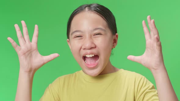 Shocked Young Asian Kid Girl Grabbing Her Head While Saying Wow On Green Screen Background