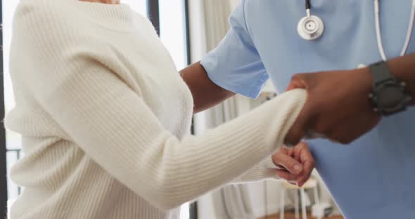 Video of midsection of african american male doctor taking care of caucasian senior woman