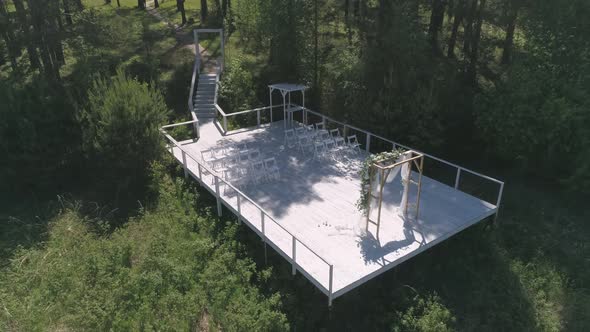 Aerial view of wedding arch on the pier by the river next to the forest 36