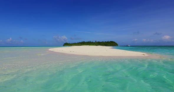 Wide angle drone tourism shot of a white sandy paradise beach and blue ocean background in colourful