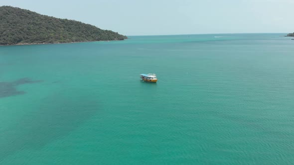 Lone Cambodian Boat in the middle of the turquoise paradisiac sea in M'pai Bay, Koh Rong Sanloem