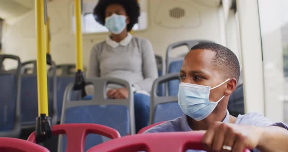 African american man and woman with face masks sitting in bus