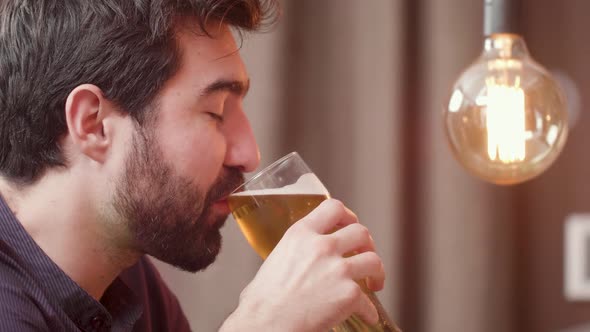 Bearded Young Man Drinks Beer and Having a Conversation with the Bartender