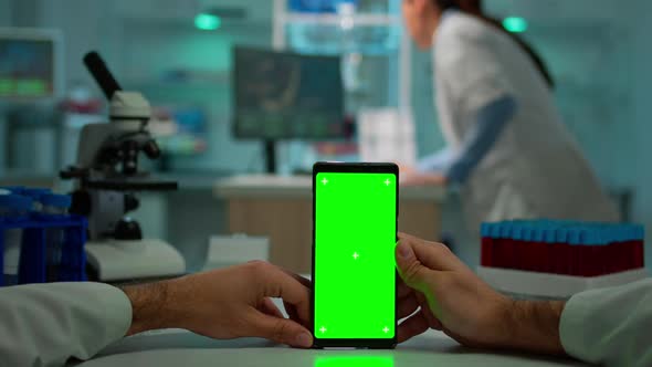 Pov Shot of Scientist Sitting at Desk Working on Mobile Phone with Green Screen