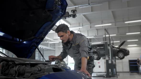 Car Service Technician Checking Oil in Automobile with Open Hood