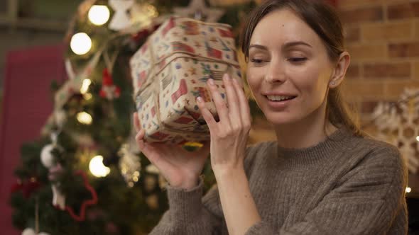 Blonde Woman Shaking Christmas Gift Box Guessing What Inside Closeup