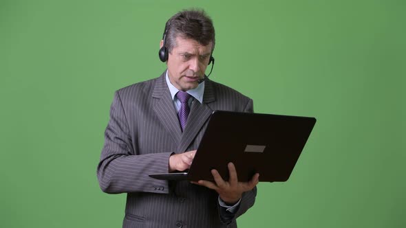 Mature Handsome Businessman Against Green Background