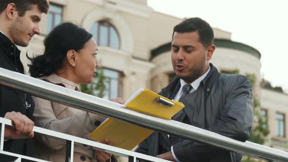 Three People Cheerfully Discuss Some Documents