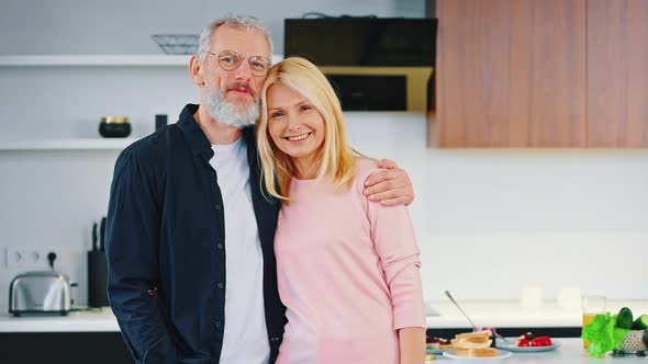 Happy Mature Couple Man and Woman Stand Embracing in the Kitchen