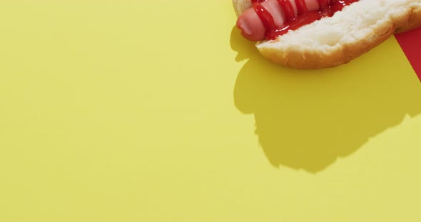 Video of hot dog with mustard and ketchup on a yellow and red surface