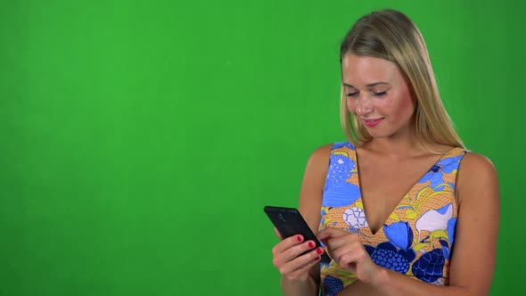 Young Pretty Blond Woman Works (Typing) on Smartphone - Green Screen - Studio