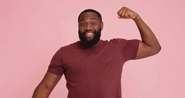 Young African American Man Demonstrate Biceps Isolated on Pink Background