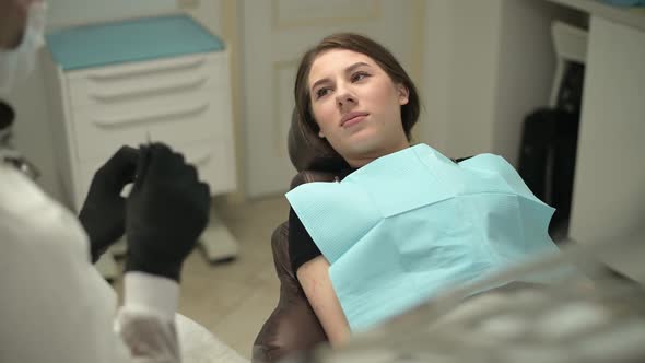 A young woman patient of a dental office listens attentively to a doctor