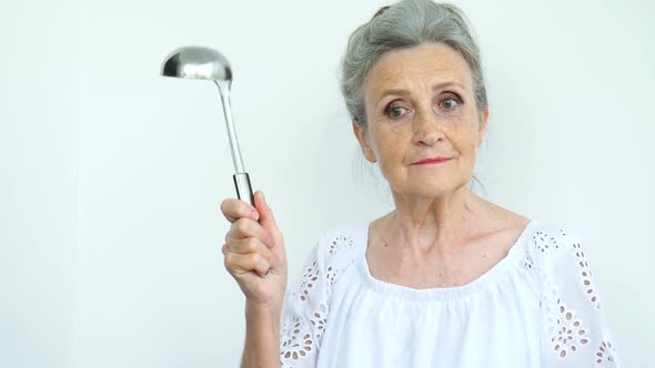 Emotional Senior Woman with Silver Hair is Holding Metal Ladle or Scoop on White Background Happy