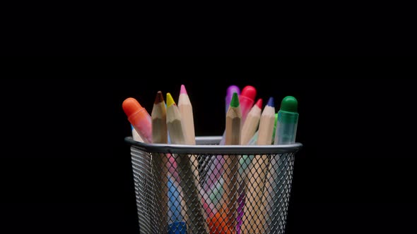 Closeup of Colored Pencils and Markers in a Metal Grey Basket Shooting Stationery on Black