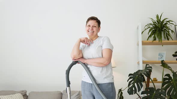 Portrait of a Senior Woman with a Vacuum Cleaner While Cleaning