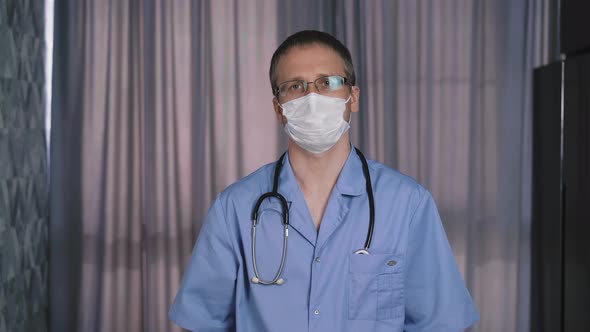 doctor in blue uniform with stethoscope puts on facial mask