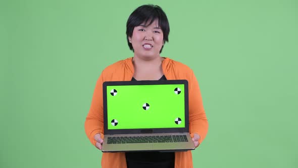 Happy Young Overweight Asian Woman Talking While Showing Laptop Ready for Gym