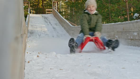 Happy Boy Sledding on Slide in Winter