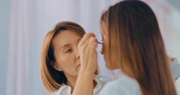 Master of the Beauty Salon Applies Mascara to the Eyelashes