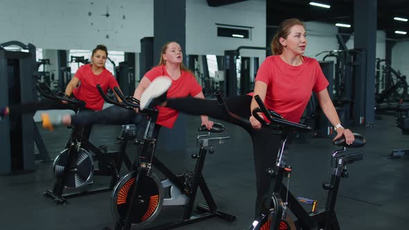 Athletic Women Group Making Stretching Training on Spinning Stationary Bike Routine in Gym Indoors