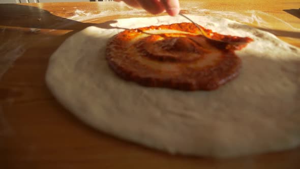 Chef Cook of Italian Food Restaurant Spreads Tomatoes Sauce on Pizza Dough Piece
