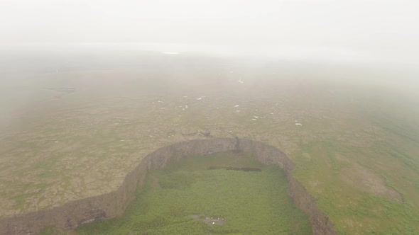 Drone Ascend Over The Clouds And Fog With Asbyrgi Canyon In Iceland. - aerial