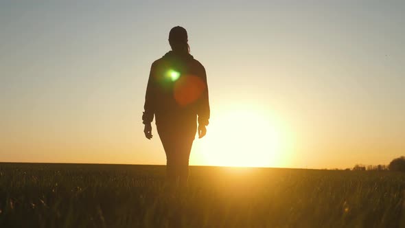 Farmer Girl Walking Beside Green Wheat Field Enjoying the Sun