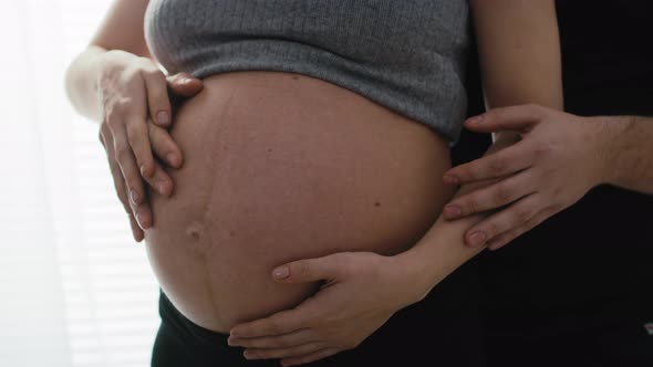 Detail of mother in advanced pregnancy and future father touching the abdomen. Shot with RED helium