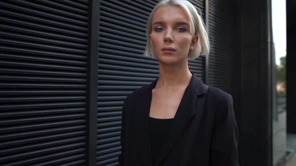 Close-up Portrait of a Young Business Girl with Short White Hair, She Walks Against a City