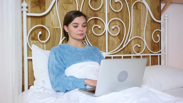 Woman in Bed Working on Laptop Gets Amazed Aand Surprised