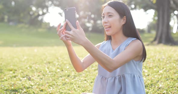 Woman using mobile phone for taking photo in the park 