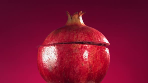 Half Pomegranate Falling and Splashing on Fuchsia Background