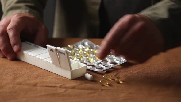 man sorts pills by day of the week in a sorter