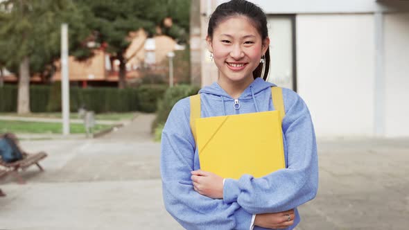 Portrait of Asian Student Woman Holding Yellow Folder and Notebooks Outside the University