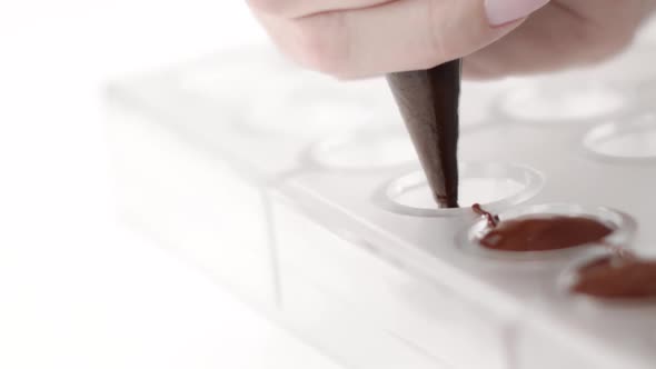 Closeup Pouring Dark Chocolate Into Confectionery Mold with Pastry Bag, Slow Mo