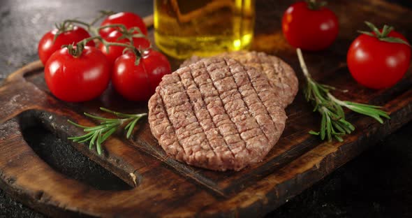 Raw Burger with Tomatoes and Oil on a Cutting Board Rotates.