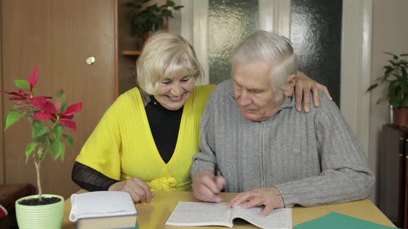 Happy Old Mature Retired Couple Sit on Table at Home Enjoying Free Time Leisure